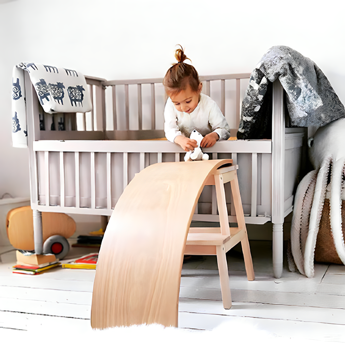 A toddler gleefully uses the Wooden Balance Board Montessori Toy as a slide for their toys, fostering imaginative play.