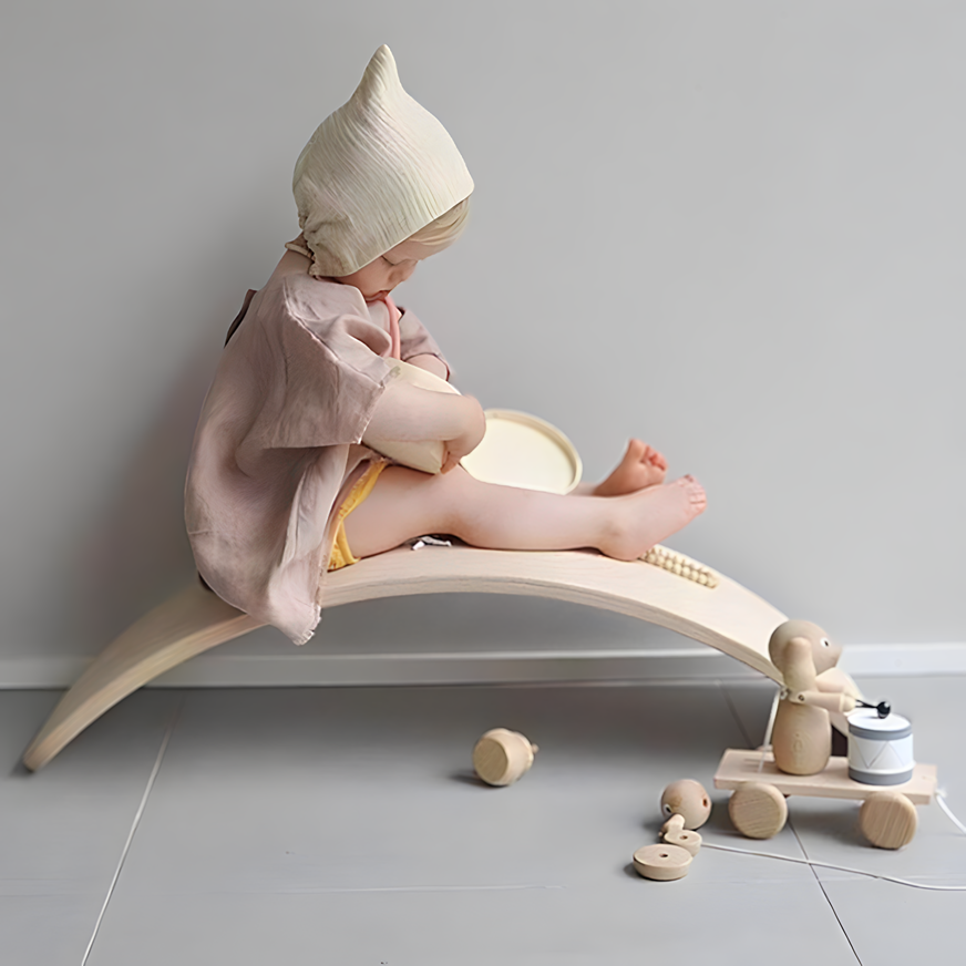 A baby happily playing with the Wooden Balance Board Montessori Toy, fostering early development and exploration.