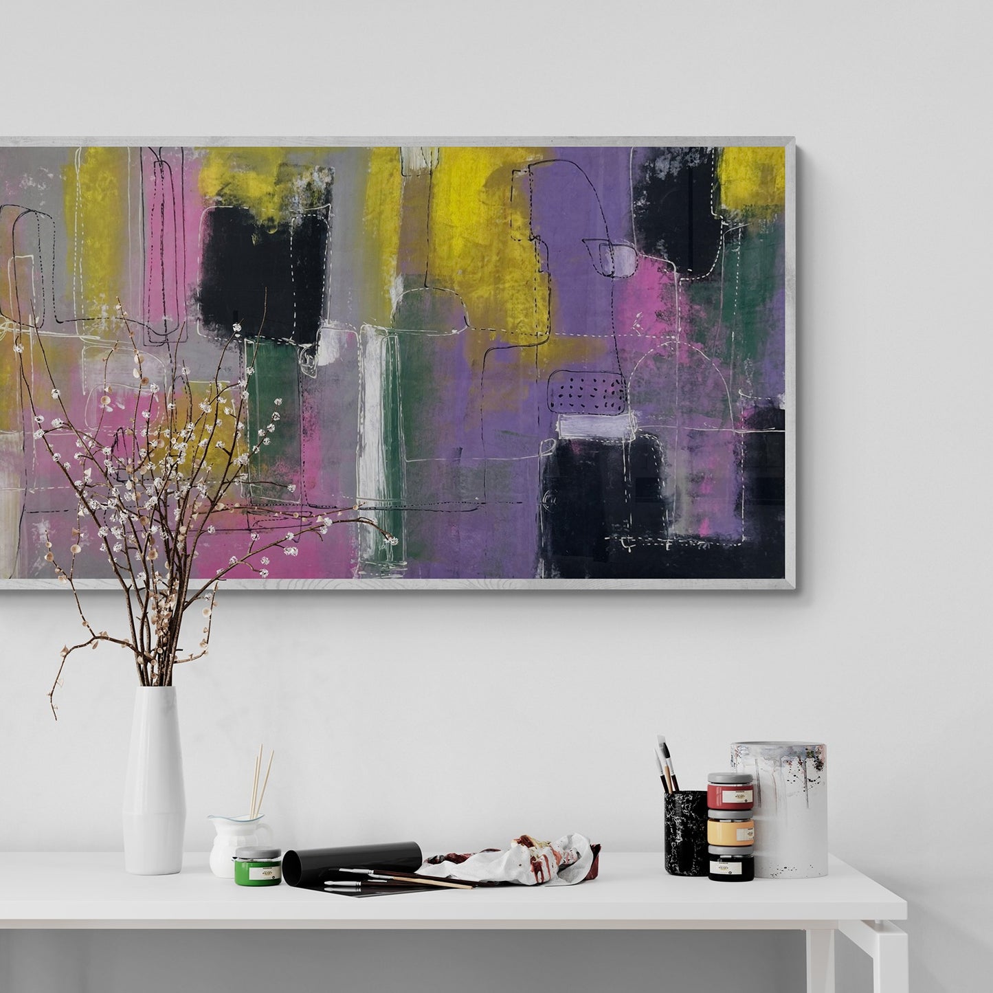 Large original abstract hand painted  wall art behind a studio table with a flowering plant
