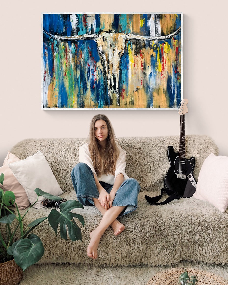 A girl sitting in her rooms sofa with a guitar and a large abstract hand painted original wall art