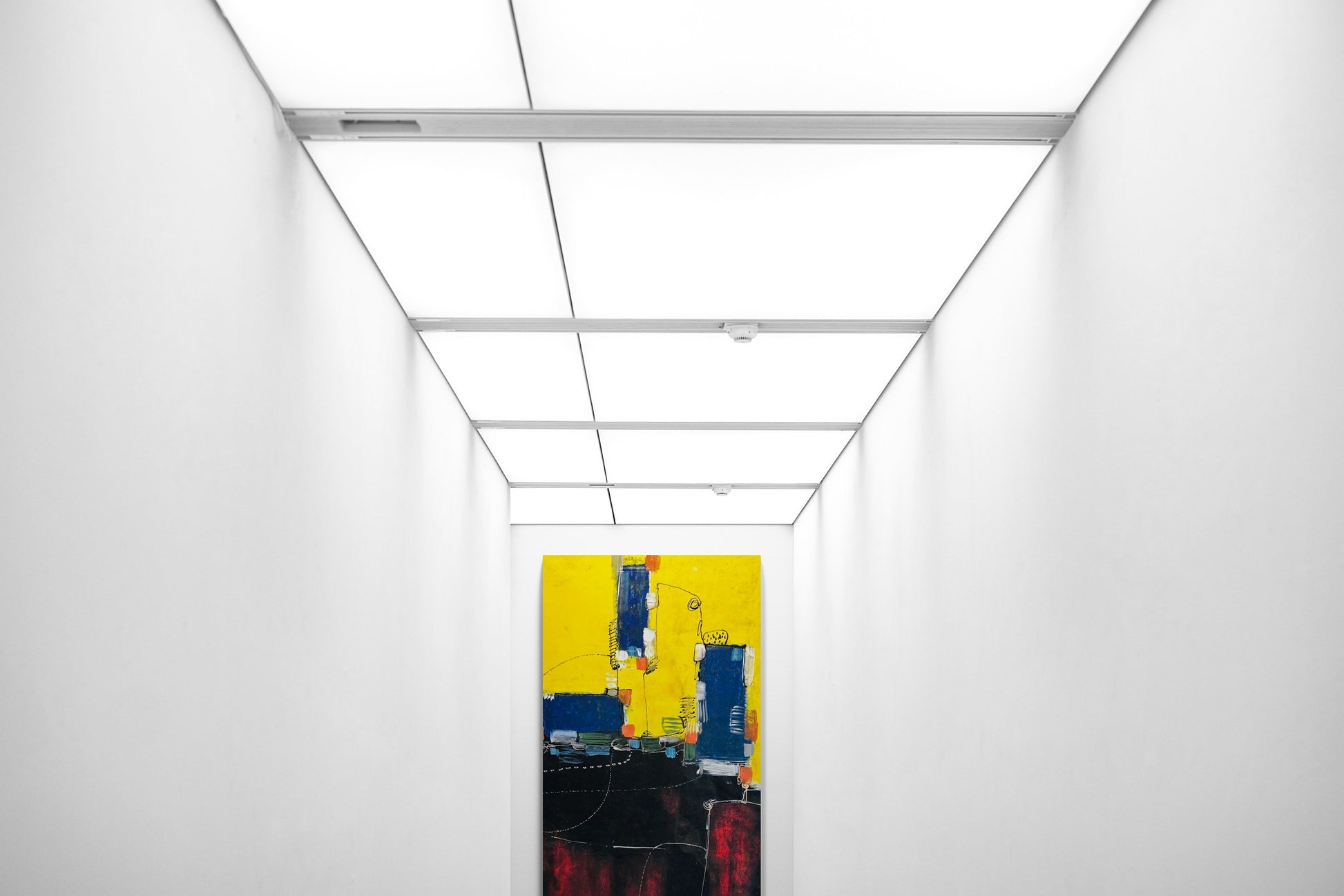 Large abstract hand painted wall art in a hallway with fluorescent ceiling light panels