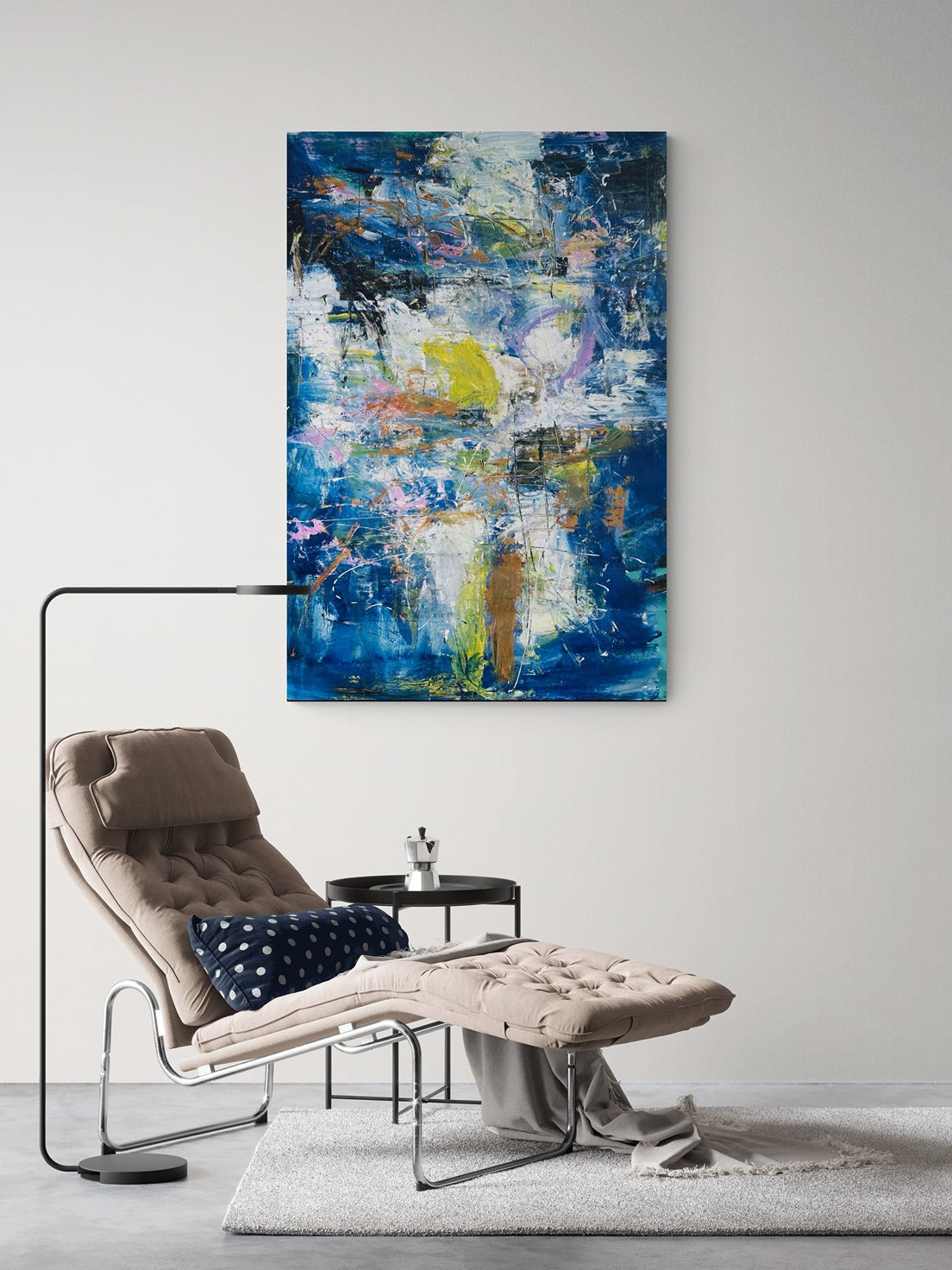 A big abstract wall art piece in a stylish sitting room with a chaise lounger and a lamp.