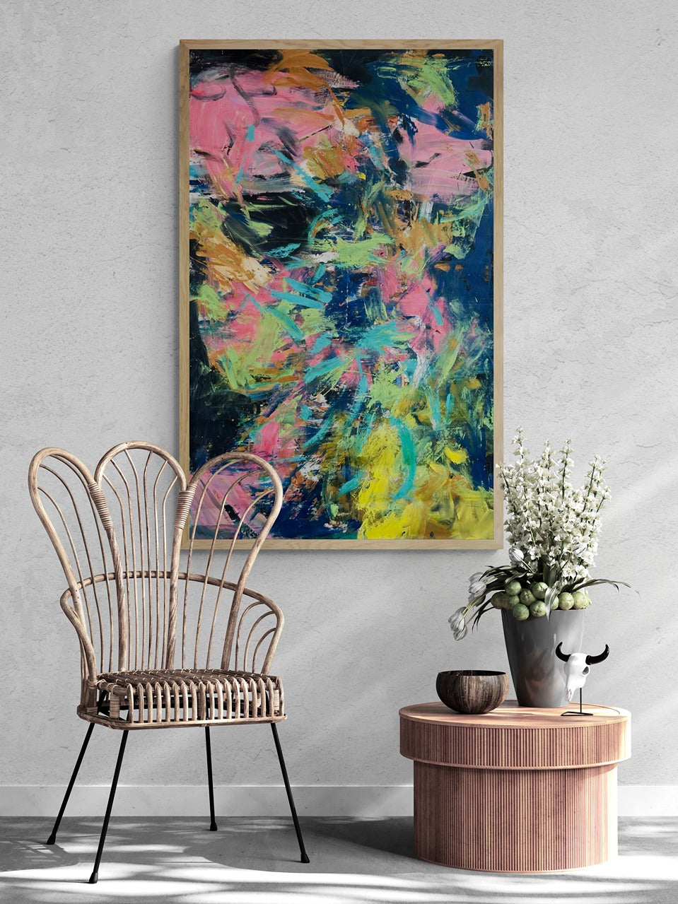 Large abstract wall art in a sunlit room with a rattan chair.