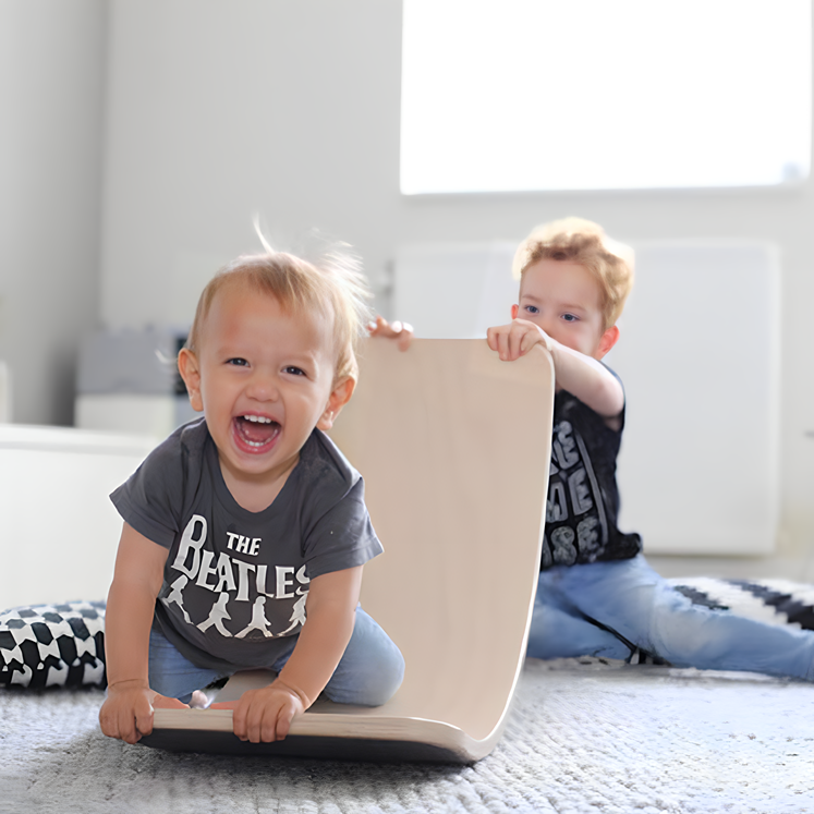 Two children happily playing with the Rasavatta Wooden Balance Board, a versatile and engaging Montessori toy.