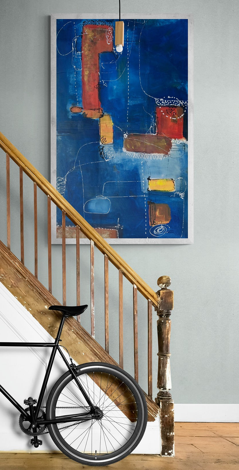 Bike leaning against hallway staircase with abstract hand-painted wall art.