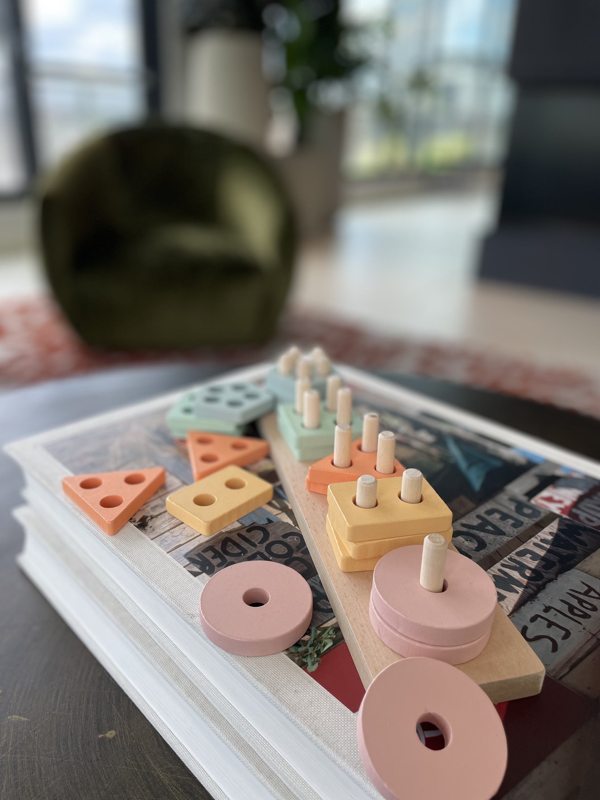 A Montessori educational wooden stacking toy with colorful rings in different shapes, stacked on a central wooden peg. The toy is designed to help young children develop fine motor skills and cognitive abilities.